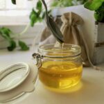 Barattolo di miele di acacia e millefiori su un tavolo, con un cucchiaio di legno accanto.