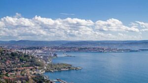 Panorama di Trieste a marzo, con il mare, il castello e un cielo limpido.